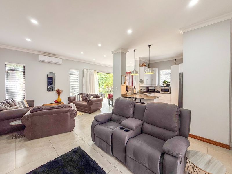 Spacious open-plan living and kitchen area featuring tiled floors, recessed lighting, modern cabinetry, and seamless access to the outdoor patio.