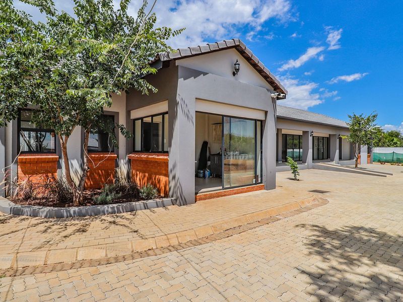 Front exterior view of a retirement village unit featuring paved driveway, brick accents, and modern sliding glass door access.