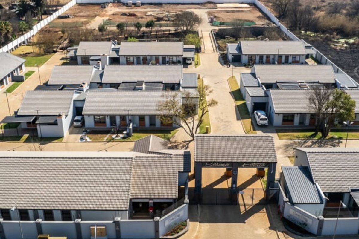 Aerial view of a retirement village complex featuring multiple residential units, a paved internal road network, and a secure gated entrance.