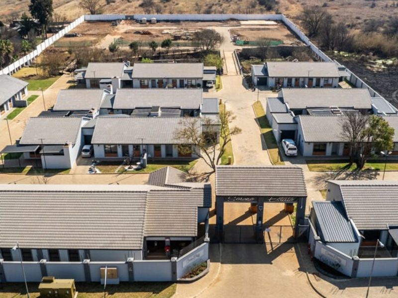 Aerial view of a retirement village complex featuring multiple residential units, a paved internal road network, and a secure gated entrance.