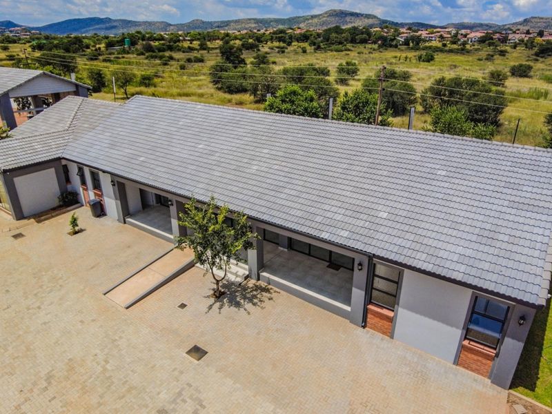 Aerial view of a retirement village building featuring a tiled roof, paved driveway, and accessible wheelchair ramp entry.