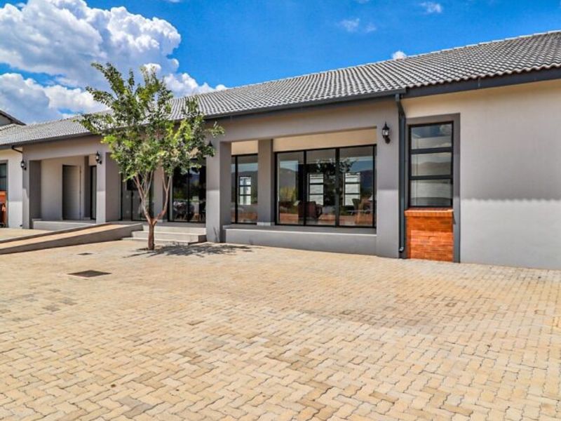 A well-maintained exterior view of a retirement village unit featuring a paved driveway, modern aluminium window frames, and a clean tiled roof.