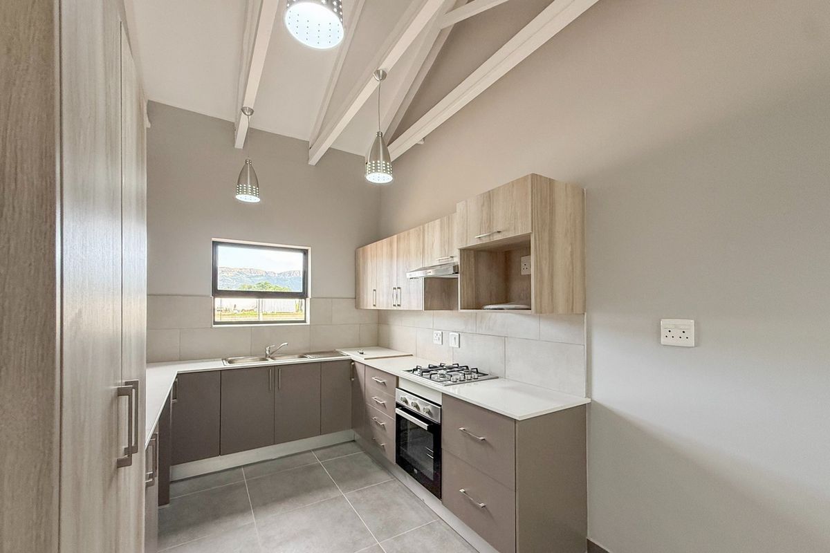 Modern kitchen featuring light wood-tone cabinetry, gas hob, electric oven, tiled splashback, and exposed ceiling beams with pendant lighting.