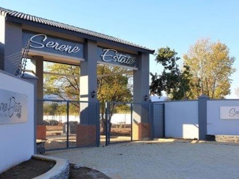 The main entrance to Serene Estate, featuring a secure gated access point, perimeter walling with electric fencing, and paved driveway.