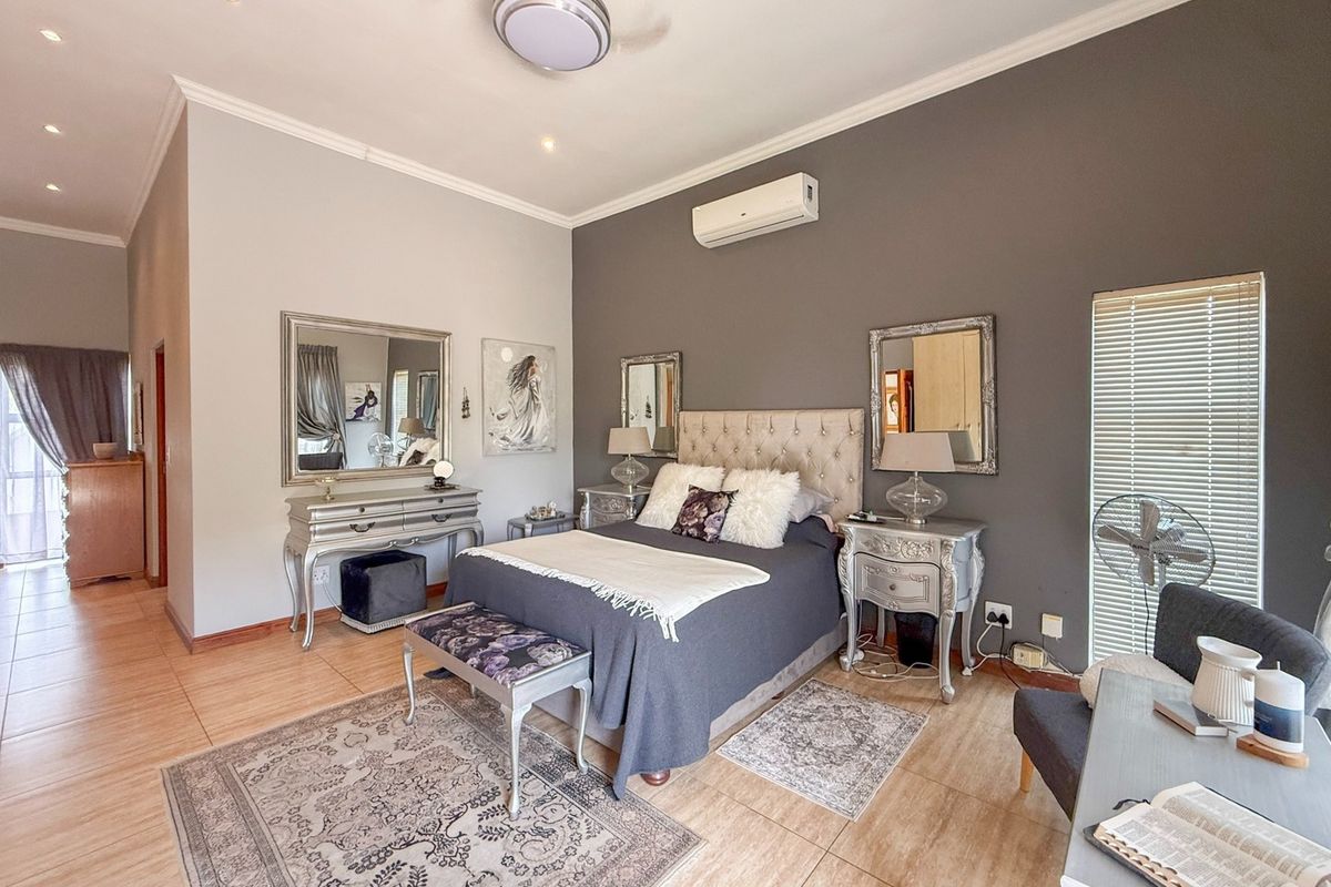 A well-maintained bedroom featuring tiled flooring, a ceiling fan, and a wall-mounted split-system air conditioner, with neutral wall tones and recessed lighting.