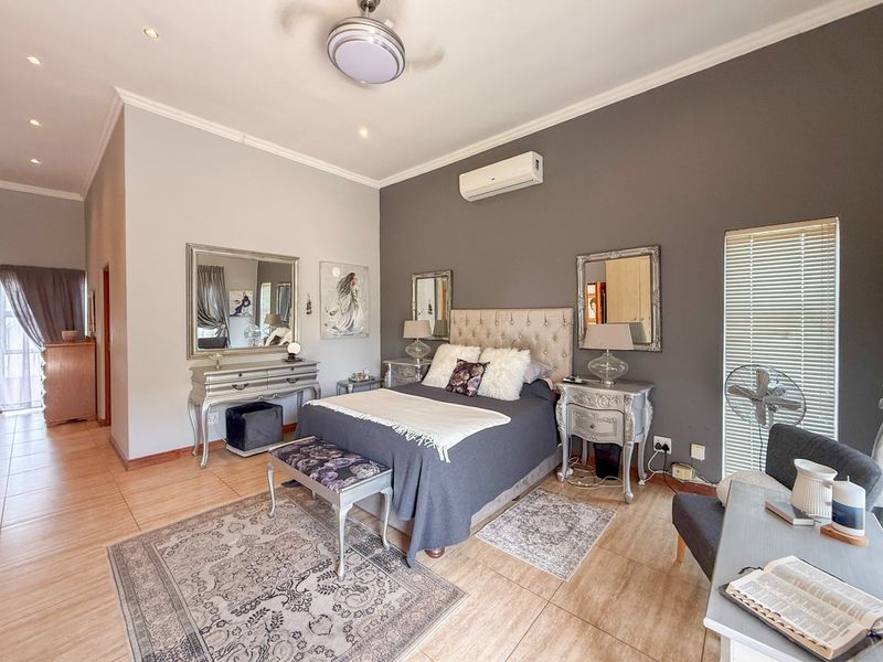 A well-maintained bedroom featuring tiled flooring, a ceiling fan, and a wall-mounted split-system air conditioner, with neutral wall tones and recessed lighting.