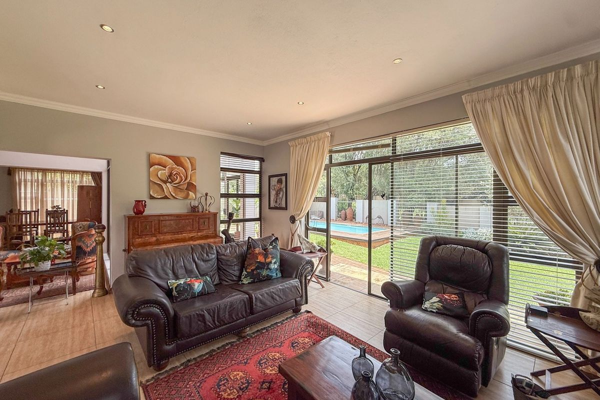 A well-lit living room featuring tiled floors, recessed lighting, and large sliding glass doors providing direct access to the garden and pool area.