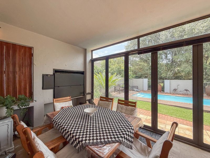 Covered patio area featuring a built-in braai and large sliding glass doors overlooking the swimming pool and garden.