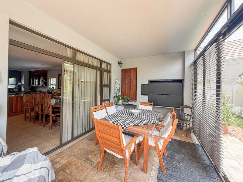 Covered patio featuring a built-in braai, tiled flooring, and large sliding glass doors providing seamless access to the interior living area.