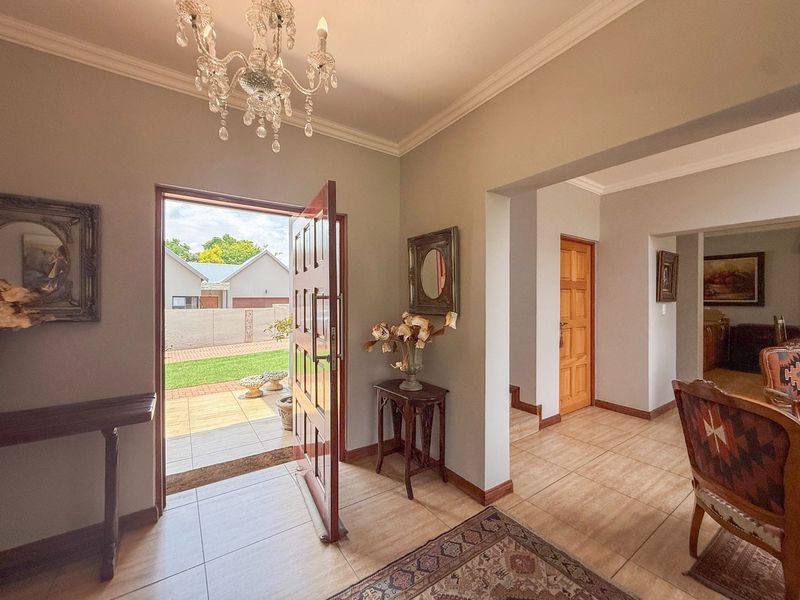 Welcoming entrance hall featuring tiled flooring, a classic crystal chandelier, and direct access to the outdoor patio area.