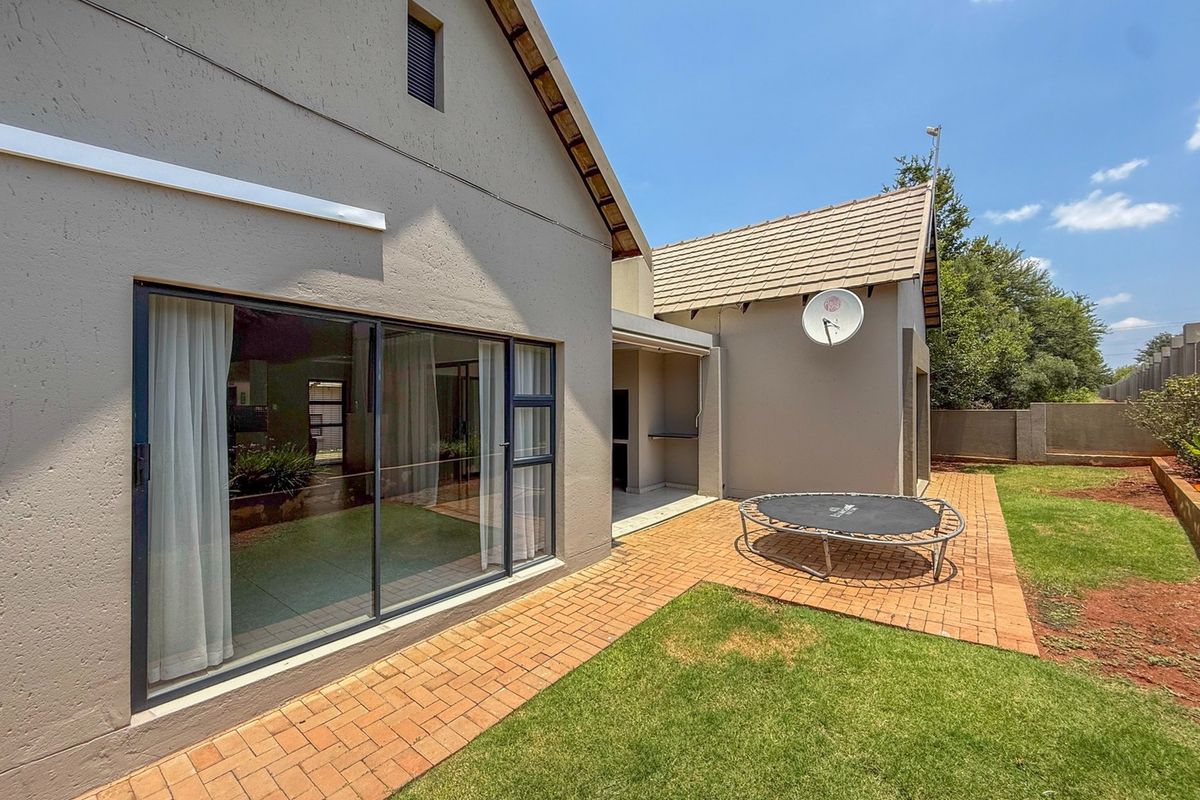 Rear view of the townhouse featuring a paved patio area, sliding glass doors, and a private garden space.