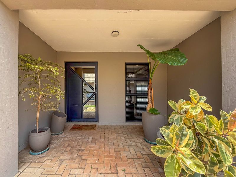 A covered entrance porch featuring paved flooring, a modern front door, and a fixed window, providing a welcoming and well-maintained entry to the townhouse.