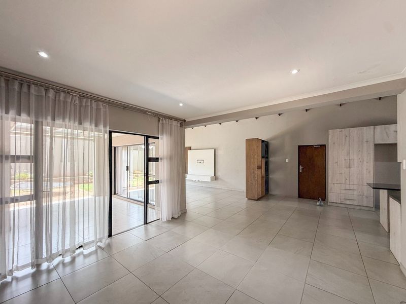 Spacious open-plan living area featuring large format floor tiles, recessed lighting, and seamless access to the outdoor patio through sliding glass doors.