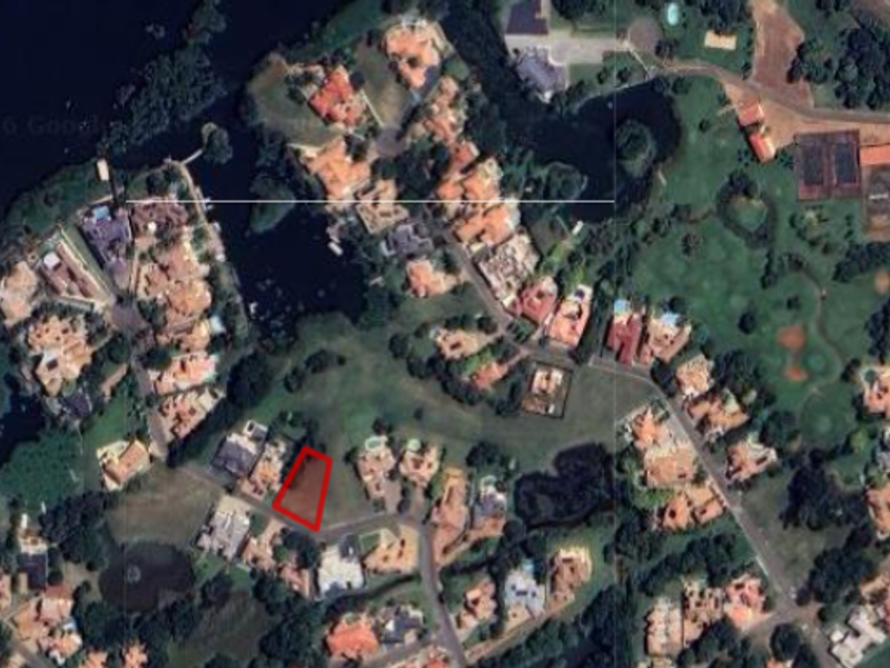 Aerial view of a vacant residential plot highlighted in red, situated within a developed estate with surrounding homes and green spaces.