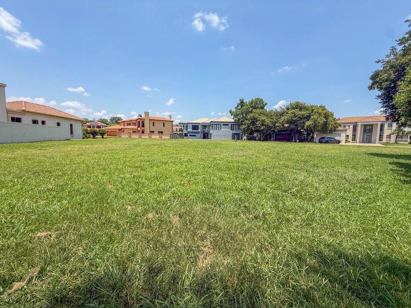 A spacious, level residential vacant land plot featuring a well-maintained grass lawn and established boundary walls in a developed neighborhood.