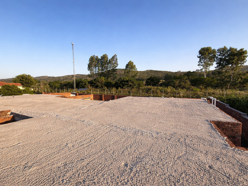 An elevated view of an unfinished property showing exposed brick walls and a concrete slab roof under construction.