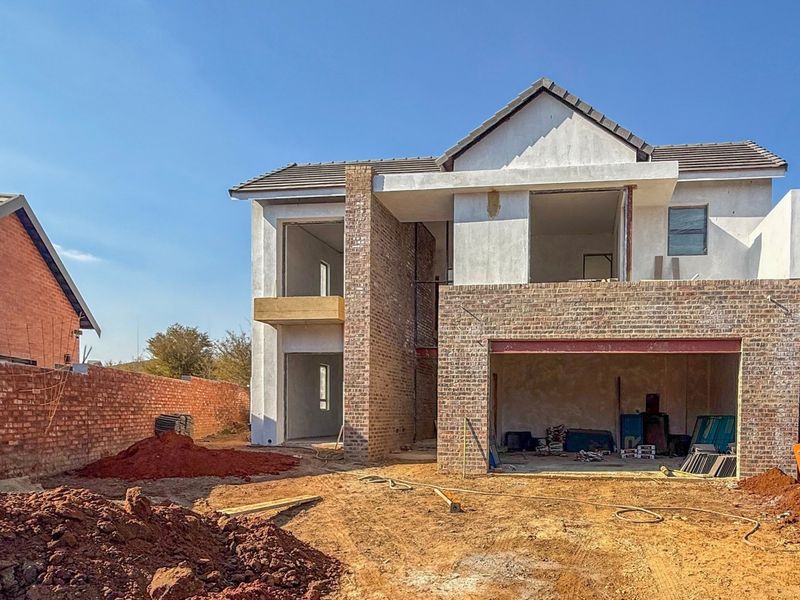 A two-story residential property under construction, featuring a brick facade, double garage, and an unfinished exterior site.
