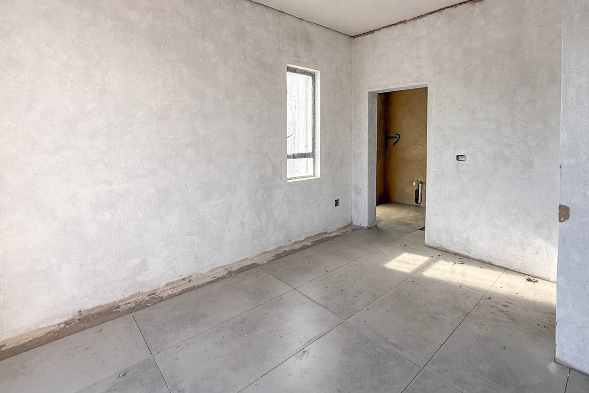 An unfinished bedroom interior featuring tiled flooring and plastered walls, currently in a shell condition awaiting final finishes and trim.