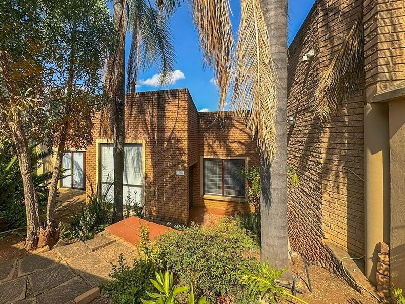 Front elevation of a face brick house featuring a paved entrance path and established garden surroundings.