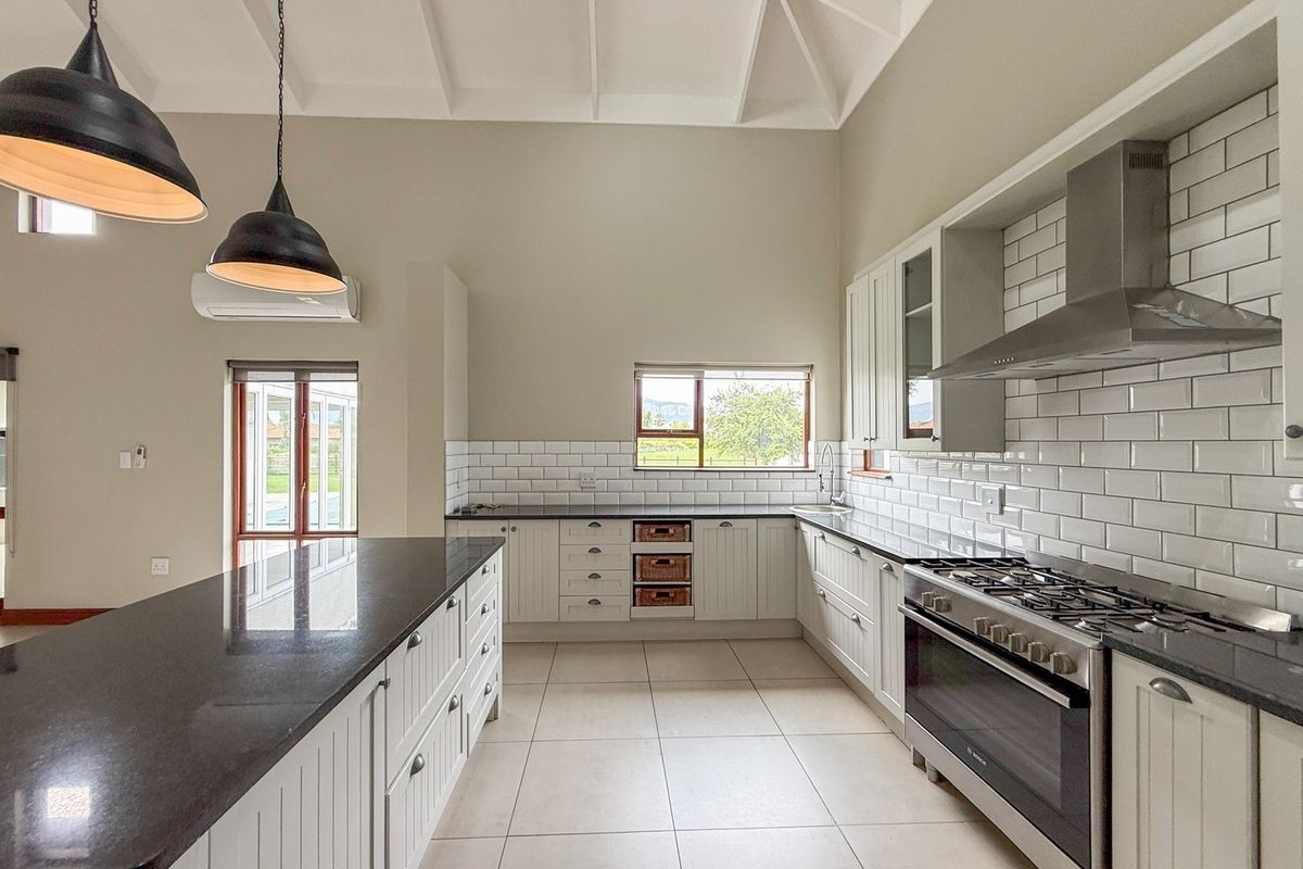 Modern kitchen featuring vaulted ceilings, granite countertops, subway tile backsplash, a large central island, and high-quality stainless steel appliances.
