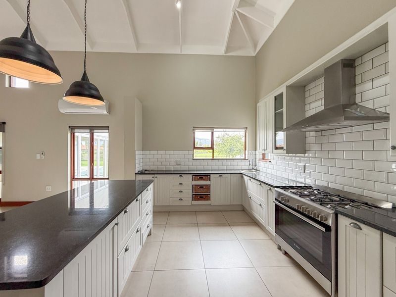 Modern kitchen featuring vaulted ceilings, granite countertops, subway tile backsplash, a large central island, and high-quality stainless steel appliances.