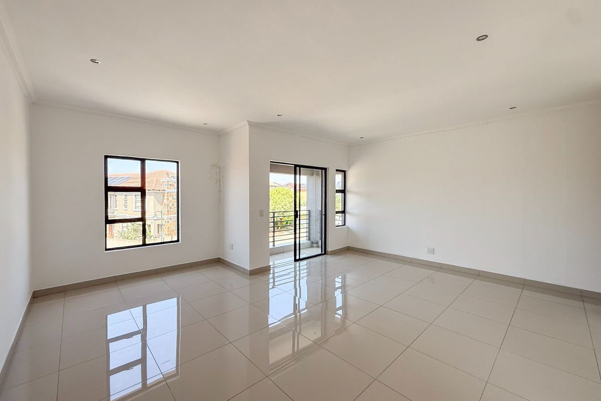 A bright, spacious, and empty living area featuring polished porcelain floor tiles, recessed lighting, and direct access to a balcony through sliding glass doors.