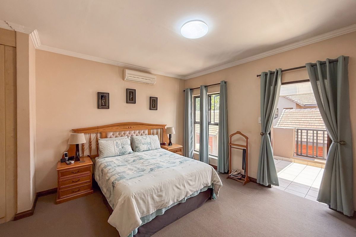 Spacious bedroom featuring carpeted flooring, built-in air conditioning, and direct access to a private balcony through a sliding glass door.