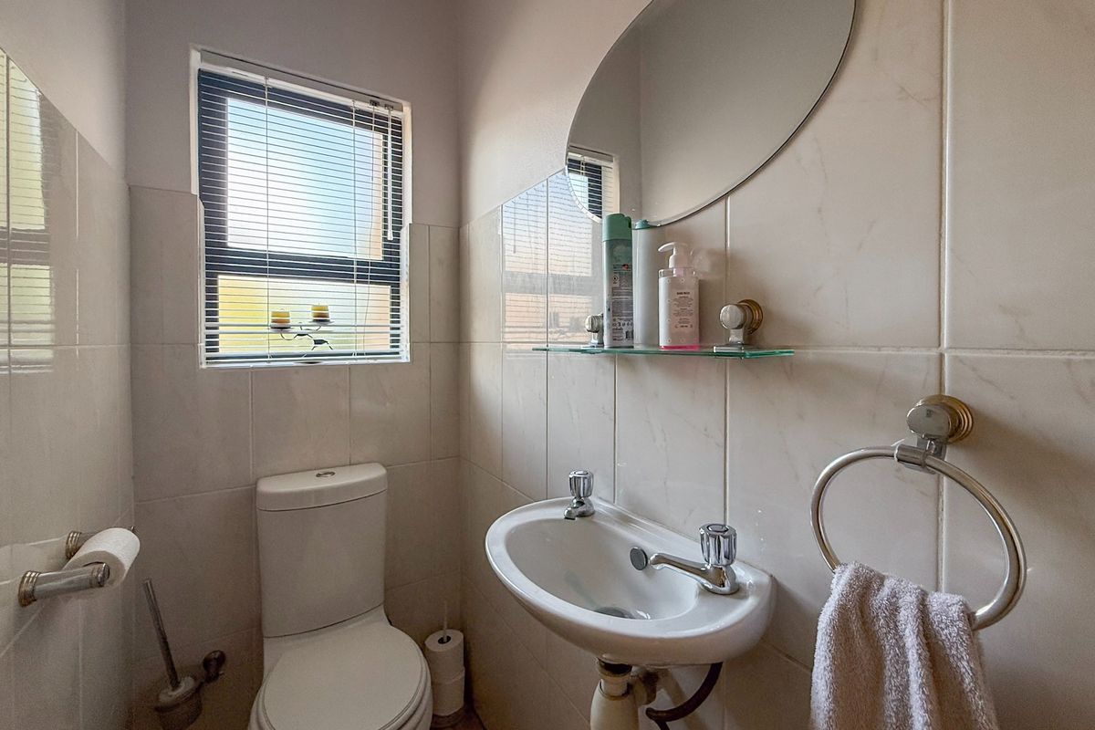 A compact guest bathroom featuring tiled walls, a wall-mounted basin, and a toilet, providing a functional and clean space.