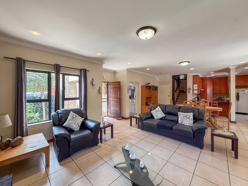 Spacious open-plan living and dining area featuring tiled floors, recessed lighting, and direct access to the kitchen and staircase.