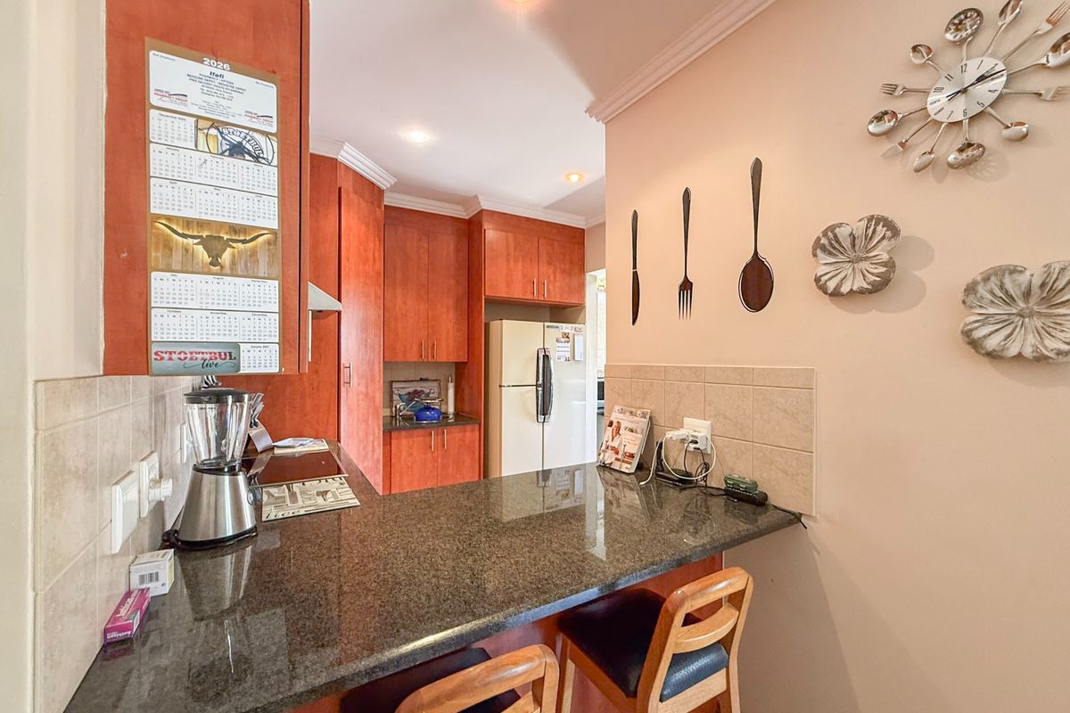 A functional kitchen featuring wooden cabinetry, granite countertops, and a breakfast bar, providing a practical space for meal preparation and casual dining.