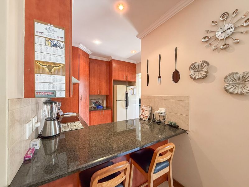 A functional kitchen featuring wooden cabinetry, granite countertops, and a breakfast bar, providing a practical space for meal preparation and casual dining.
