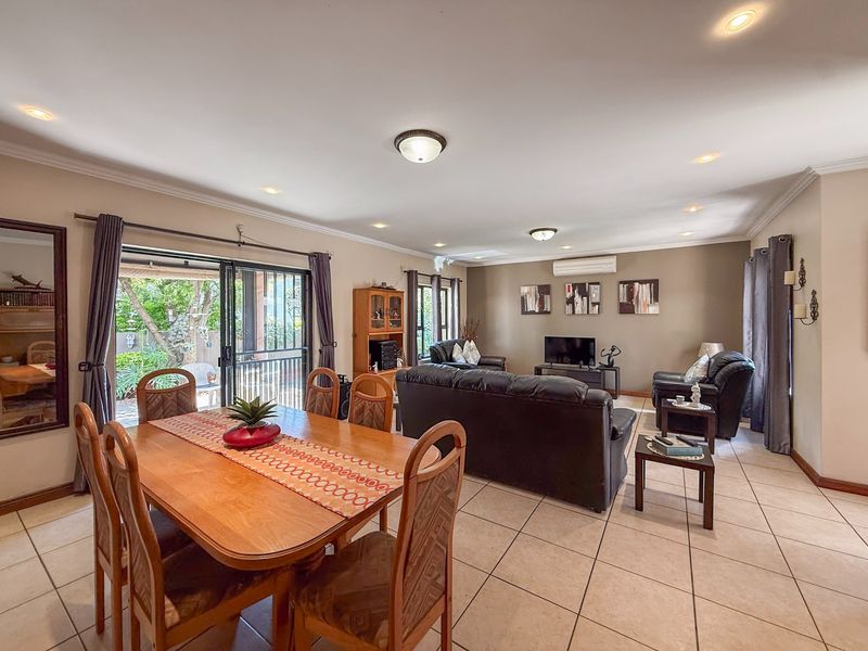 Spacious open-plan living and dining area featuring ceramic floor tiles, recessed lighting, and sliding glass doors providing access to the outdoor patio.