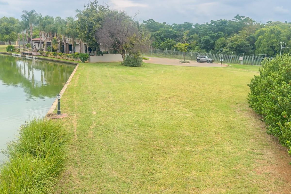 A well-maintained waterfront garden area featuring a manicured lawn, established landscaping, and direct access to the water's edge.