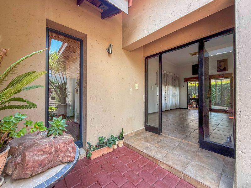 A covered patio area featuring brick paving and sliding glass doors providing access to the interior living space.