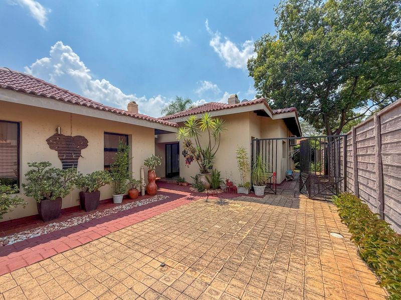 A well-maintained rear courtyard featuring paved flooring, a secure metal gate, and a precast boundary wall, providing a private outdoor space.