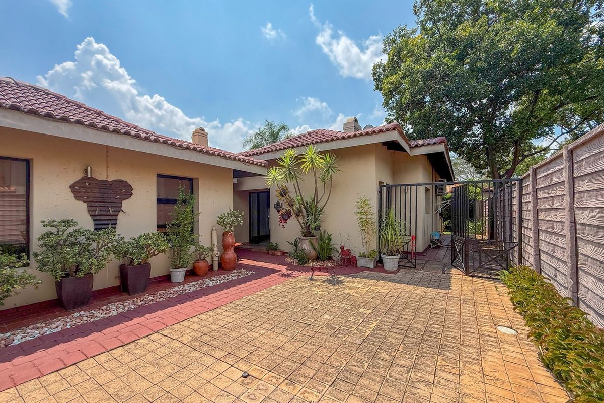A well-maintained rear courtyard featuring paved flooring, a secure metal gate, and a precast boundary wall, providing a private outdoor space.