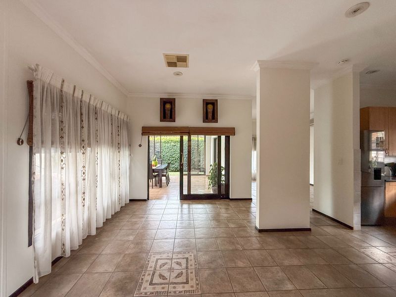 Spacious open-plan living area featuring ceramic floor tiles, recessed lighting, and direct access to an outdoor patio through sliding glass doors.