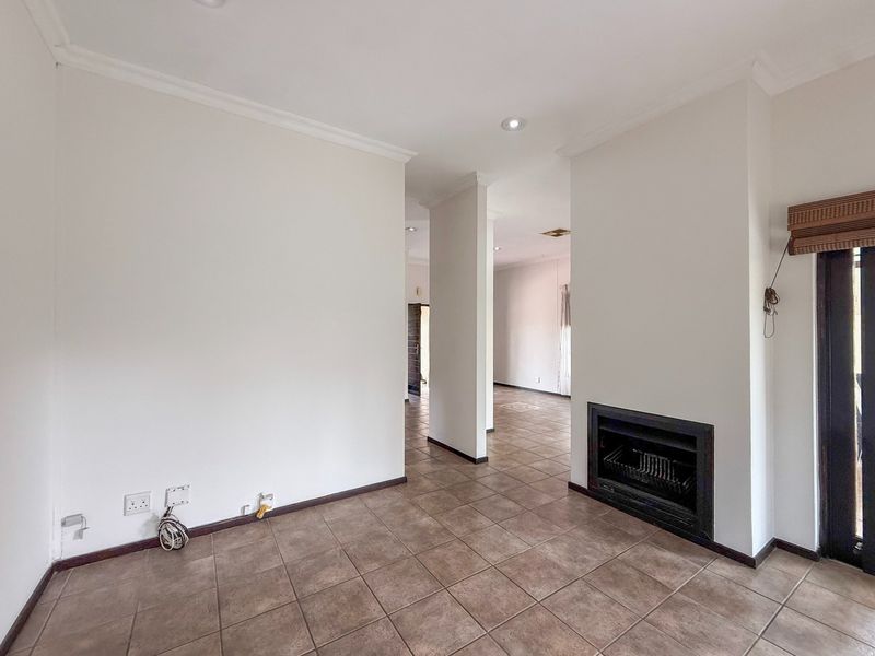 Spacious living area featuring ceramic floor tiles, a built-in fireplace, and recessed downlighting, offering a neutral blank canvas for interior design.