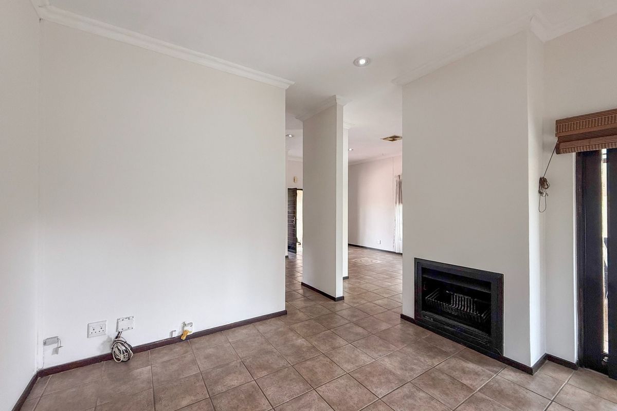 Spacious living area featuring ceramic floor tiles, a built-in fireplace, and recessed downlighting, offering a neutral blank canvas for interior design.