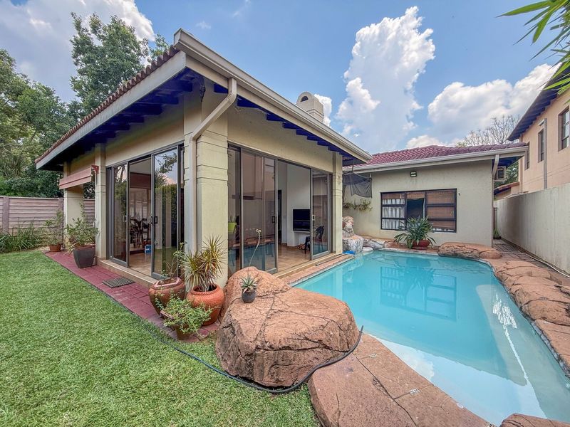 Outdoor pool area featuring a rock-edged swimming pool, tiled patio, and sliding glass doors leading into the main living space.