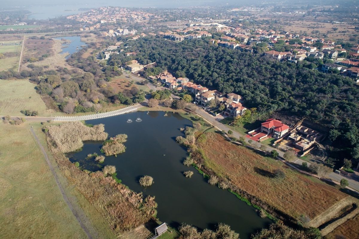 An aerial view of a residential estate featuring a large lake, surrounding wetlands, and established neighborhood infrastructure.