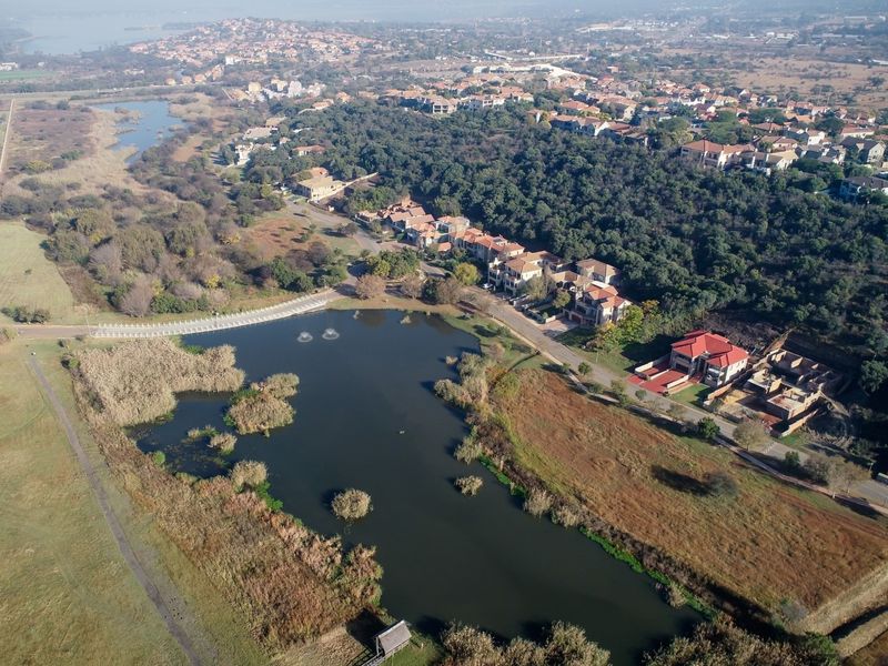 An aerial view of a residential estate featuring a large lake, surrounding wetlands, and established neighborhood infrastructure.