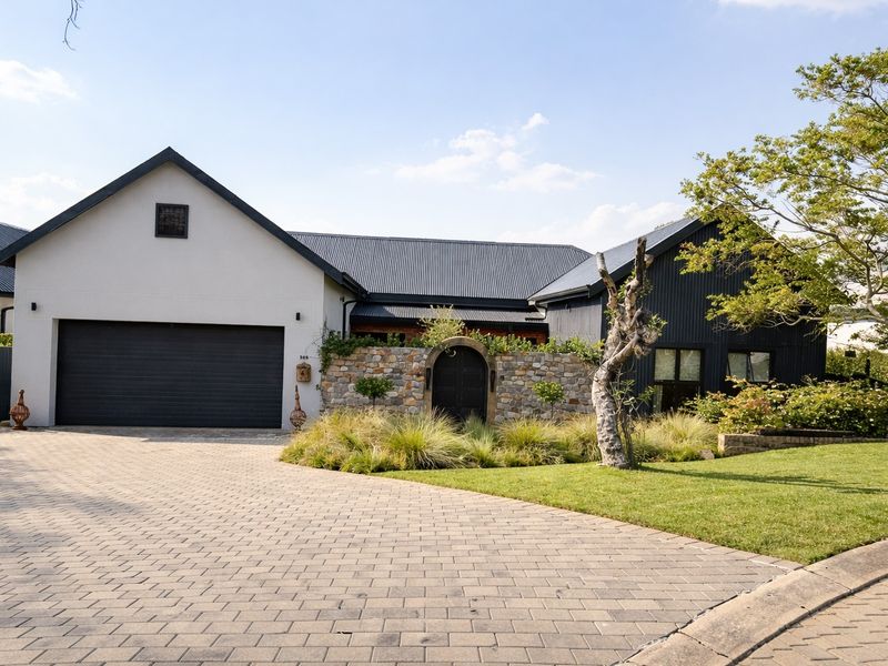 A modern, well-maintained front elevation featuring a double garage, stone feature wall, arched entrance, and a neatly paved driveway.