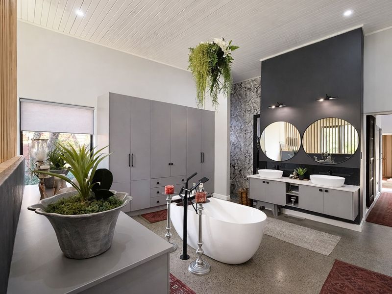 Modern, spacious bathroom featuring a sleek freestanding bathtub, double vanity with vessel sinks, and extensive built-in cabinetry with a contemporary aesthetic.