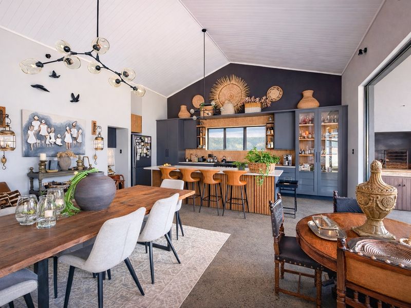 Spacious open-plan living and kitchen area featuring a vaulted ceiling, modern cabinetry, a large kitchen island, and a built-in braai.