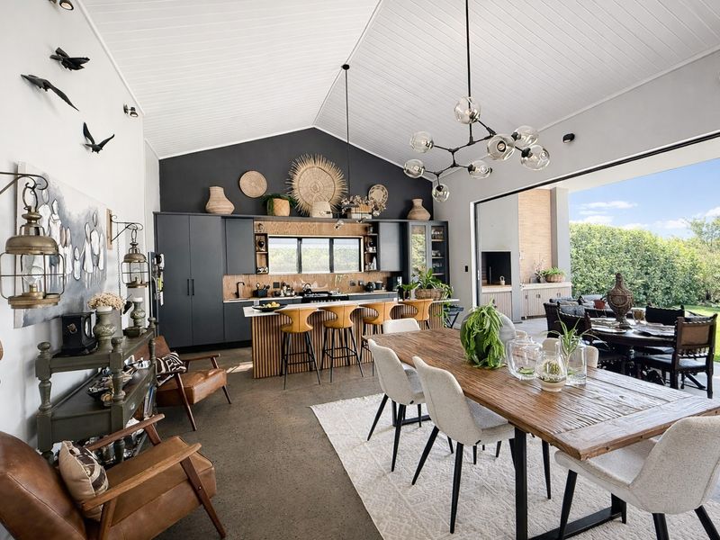 Spacious open-plan living and kitchen area featuring a vaulted ceiling, polished concrete floors, and seamless indoor-outdoor flow through large sliding glass doors.