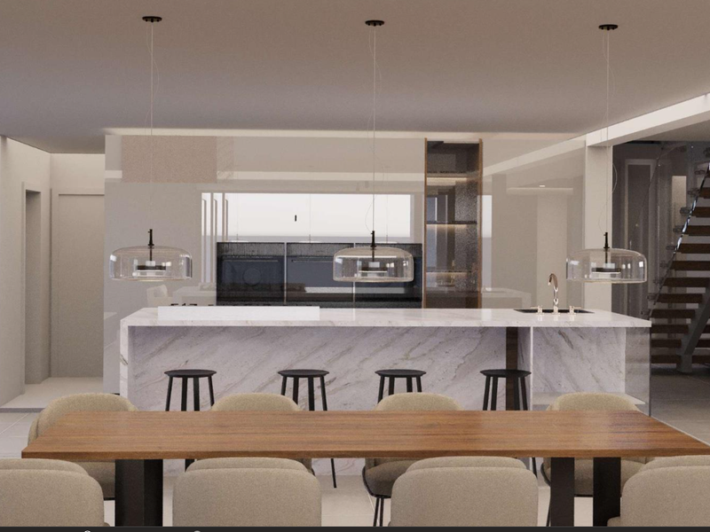 Modern open-plan living space featuring a sleek marble kitchen island, integrated appliances, and a contemporary staircase in a bright, minimalist setting.