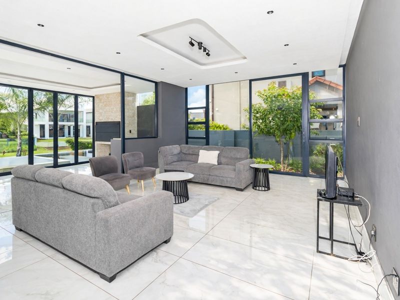 Modern open-plan living area featuring large format floor tiles, recessed ceiling lighting, and expansive glass sliding doors providing seamless indoor-outdoor flow.