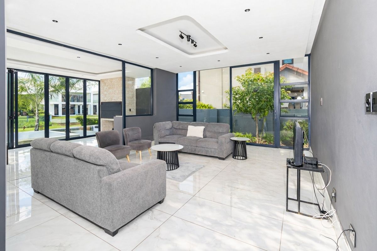 Modern open-plan living area featuring large format floor tiles, recessed ceiling lighting, and expansive glass sliding doors providing seamless indoor-outdoor flow.
