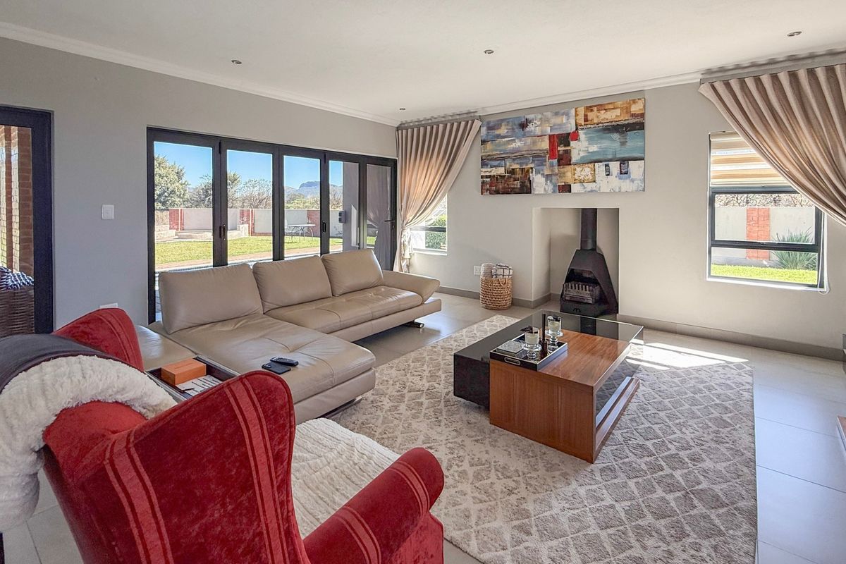 Spacious living room featuring tiled floors, a modern freestanding fireplace, and large aluminium stacker doors providing seamless access to the outdoor area.